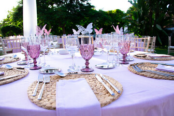 pink and white wedding table setting for a princess with decoration and butterflies in the garden or forest