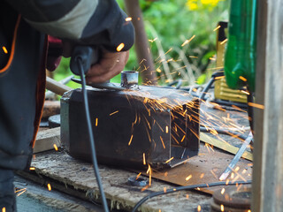 a man handles metal with an angle grinder. sparks from metal.