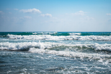 Beautiful sea waves splash with white foam on a blue ocean surface background.