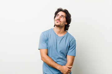 Young handsome man against a white background dreaming of achieving goals and purposes