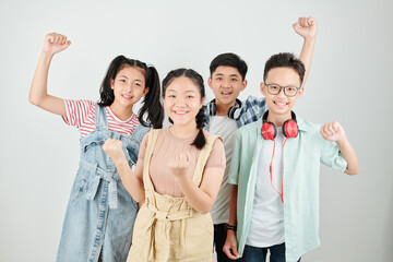 Group of happy Vietnamese school children raising hands and smiling at camera