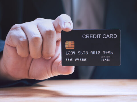 Businessman holding or showing black creadit card for shopping online. E-commerce, commercial, payment concept.