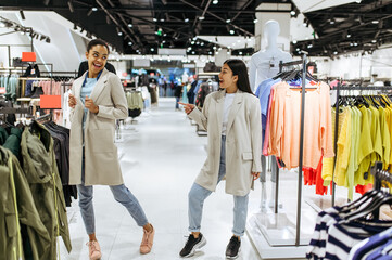 Two girls trying on coats in clothing store