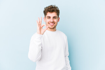 Young blond curly hair caucasian man isolated cheerful and confident showing ok gesture.