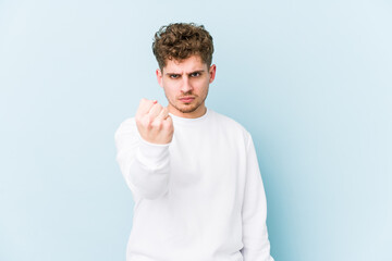 Young blond curly hair caucasian man isolated showing fist to camera, aggressive facial expression.