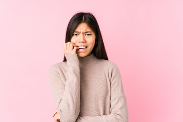 Young chinese woman posing isolated biting fingernails, nervous and very anxious.