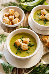 Vegetable creamy zucchini and herb soup with garlic croutons in a white bowl on a wooden  table top view