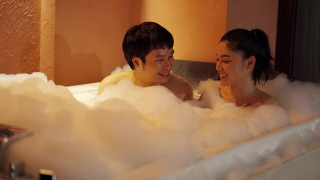 young couple taking a bubble bath in the bathtub at the night