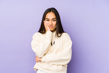 Fototapeta premium Young woman isolated on a purple background who is bored, fatigued and need a relax day.