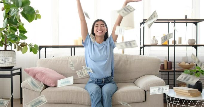 Rich woman throwing dollar bills in air at home