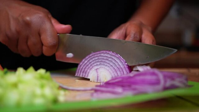 Thinly and carefully slicing a juicy red oinion for a fresh and healthy salad recipe - isolated slow motion