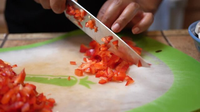 Dicing and chopping fresh red bell peppers to add to a vegetarian recipe - slow motion