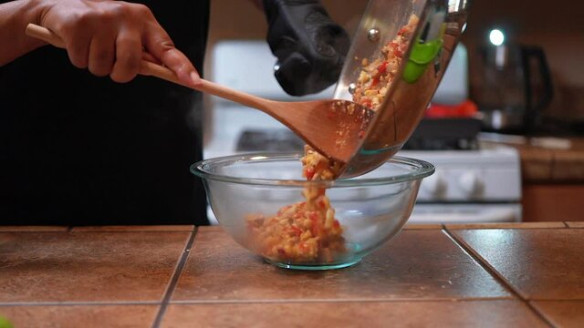 Dumping freshly cooked vegetarian stuffing in a glass bowl from the frying pan - slow motion