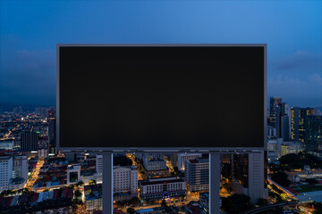 Blank black road billboard with Kuala Lumpur cityscape background at night time. Street advertising poster, mock up, 3D rendering. Front view. Concept of marketing to promote or sell idea or product. © VideoFlow
