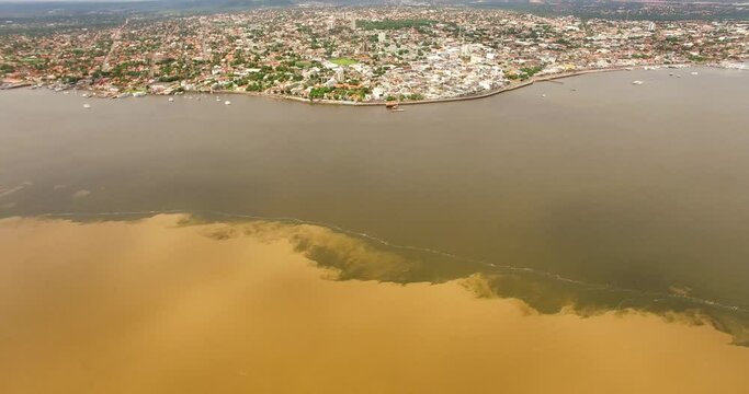 Aerial view of the meeting of the brown waters of the Amazon River and the dark waters of the Tapajos River, in front of the town of Santar&eacute;m, Par&aacute; state, Brazil