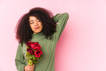Young afro woman holding a roses isolated Young afro woman holding a rosestouching back of head, thinking and making a choice.