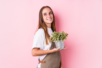 Young gardener caucasian woman isolated looks aside smiling, cheerful and pleasant.