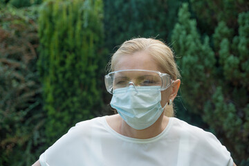 Mature woman wearing goggles and facemask. Coronavirus protection