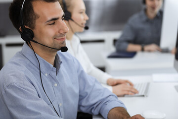 Call center. Group of casual dressed operators at work. Adult businessman in headset at customer service office. Telesales in business