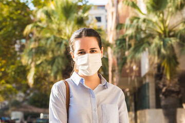 Stock photo of a young woman wearing a face mask looking at camera in the street