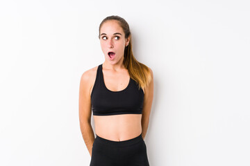 Young caucasian fitness woman posing in a white background being shocked because of something she has seen.