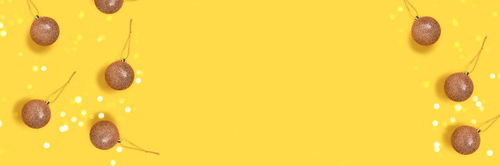 Border frame made of scattered golden Christmas toys on a yellow background. Festive banner with place for your design.
