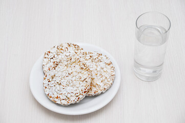 Crispy dietary bread on white plate and a glass of water. Vegetarian breakfast.