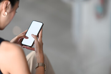 Cropped image of a woman's hands is using a mobile phone with a white blank screen.