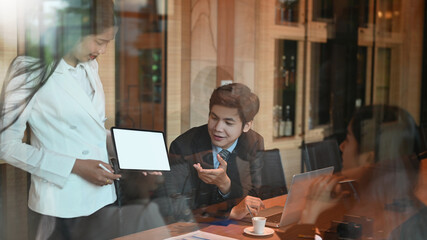 A businesswoman is presenting her project in the meeting room surrounded by businesspeople.