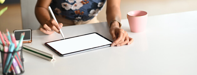 Cropped shot designer is sketching on a white blank screen computer tablet.