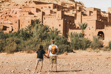 Couple of backpacker travelers on background Ait Ben Haddou ksar in Ouarzazate. Welcome to Morocco. Travel concept. Popular landmark.