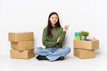 Young chinese woman moving to a new home smiling cheerfully pointing with forefinger away.