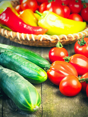 Harvest of fresh ripe vegetables on wooden table and in rod bowl - pepper, tomato, cucumber. Healthy organic food, summer vitamins, BIO viands, natural background