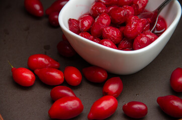 red dogwood berries and a bowl of jam on a dark background