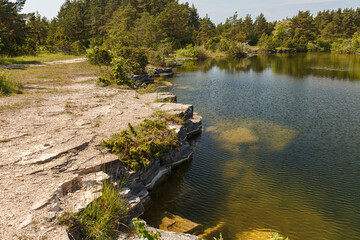 Old stone quarry filled with emerald water. Saaremaa island, Estonia.
