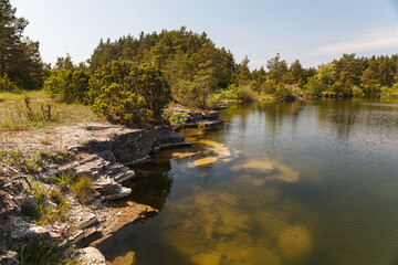 Fototapeta na wymiar Old stone quarry filled with emerald water. Saaremaa island, Estonia.