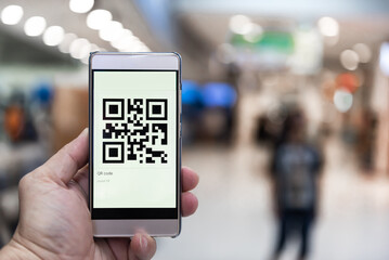 Hand holding mobile phone with COVID-19 QR Code in the shopping mall.