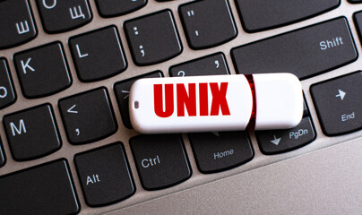 UNIX - the word on a white flash drive, lying on a black laptop keyboard