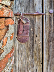 An old wooden door with a rusty iron lock and a padlock.