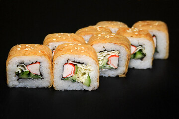 Sushi roll with omelet and crab on black background.