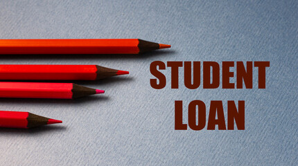 STUDENT LOAN - text on gray paper with red pencils lying next to