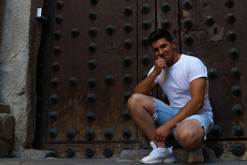 Man with a white T-shirt and a brown door in the background