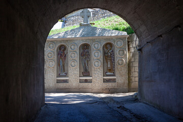 Frescoes in the form of icons at the entrance to the monastery. Above the frescoes there is an inscription in Russian "St. Clement Monastery". Crimea.
