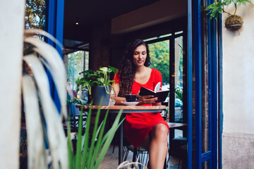 Ethnic young lady with interesting book in cafe