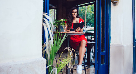Obraz premium Content woman sitting at table with book in cafe
