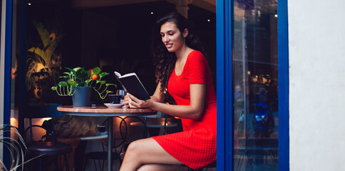 Fototapeta na wymiar Positive ethnic lady with book in cafe