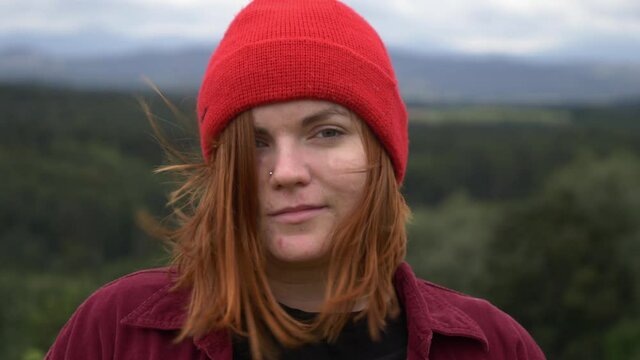 young girl in red hat without makeup looking in camera with mountains on background