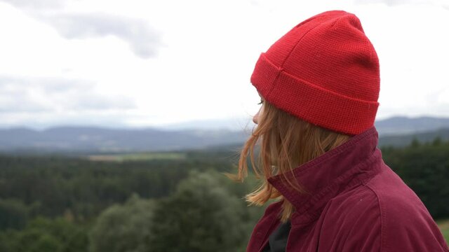 young girl in red hat without makeup looking on mountains