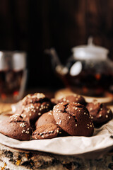 Teapot with black tea and homemade chocolate cookies on a brown natural wooden background