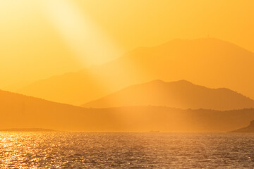 Fototapeta na wymiar sunset over the sea, mountain on horizon.